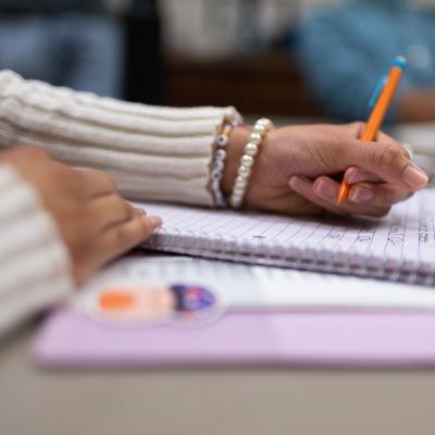 A closeup of a hand holding a pencil above a notebook.